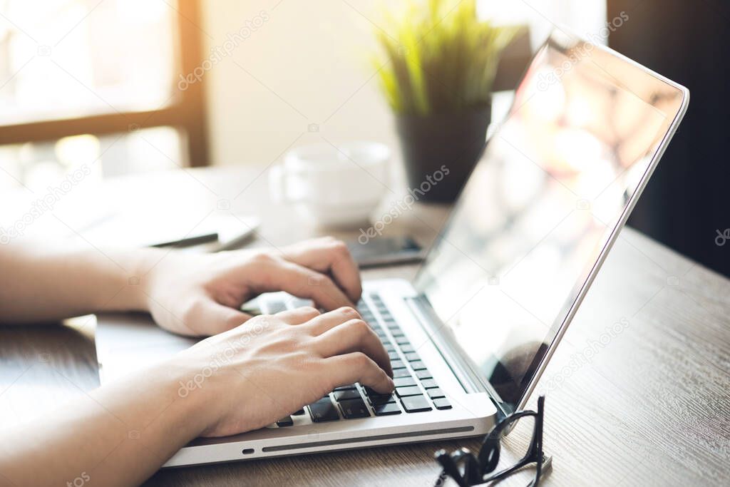 Man hands typing on laptop keyboard with sun light in the morning. Internet research concept.