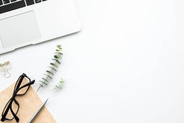 Laptop, defter ve malzemelerle dolu beyaz ofis masası. Kopyalama alanı olan üst görünüm, düz yatay.