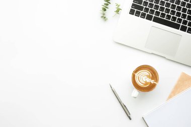 Laptop bilgisayarı, kahve ve malzemelerle dolu beyaz ofis masasının üst görüntüsü. Asgari biçim, düz yatış.