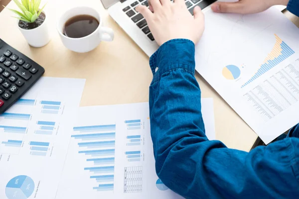 Businessman is inspecting the business reports graphs and typing on computer keyboard to audit the financial reports. Analyzing the revenue and auditing the budget concept.