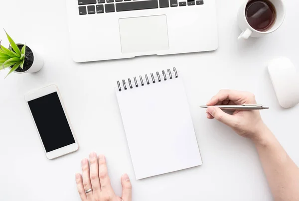 White minimalist office desk table with man going to write something on blank notebook page. Top view, flat lay.