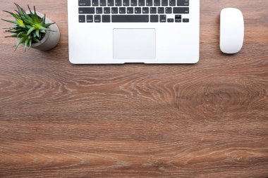 Minimalist ahşap ofis masası ve fareli dizüstü bilgisayar. Kopyalama alanı olan üst görünüm, düz yatay.