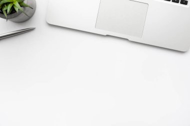 Laptop bilgisayarı, kaktüs tenceresi ve kalemle dolu beyaz ofis masası. Kopyalama alanı olan üst görünüm, düz yatay.