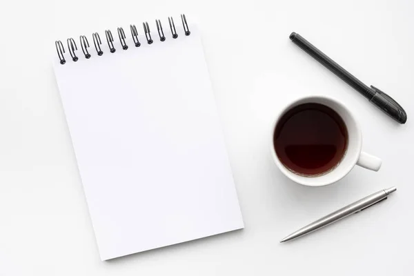 ペン付きの空白のノートブックは コーヒーカップ付きの白いオフィスデスクテーブルの上にあります コピースペース フラットレイ付きのトップビュー — ストック写真