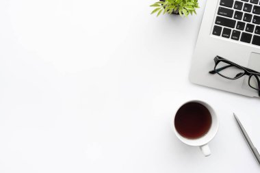 En az beyaz ofis masası. Laptop bilgisayar, bir fincan kahve ve ofis malzemeleriyle. Kopyalama alanı olan üst görünüm, düz yatay.