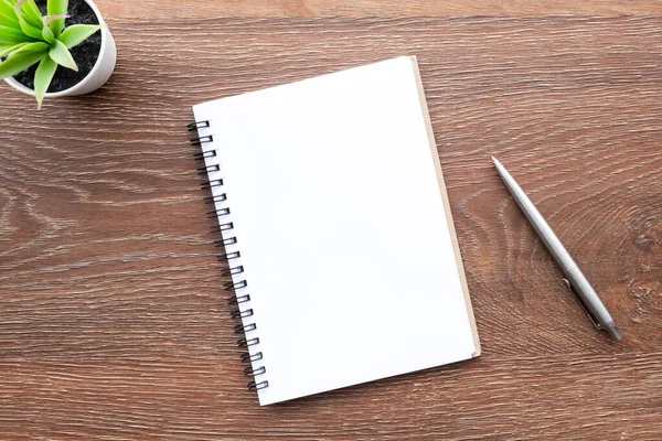 木製のオフィスデスクテーブルの上にペン付きの空白のノートブックがあります トップビュー フラットレイアウト — ストック写真