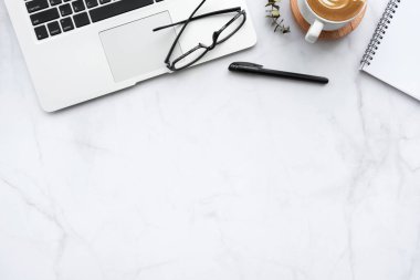 Laptop bilgisayarlı mermer masa masası, bir fincan kahve ve malzeme. Kopyalama alanı olan üst görünüm, düz yatay.