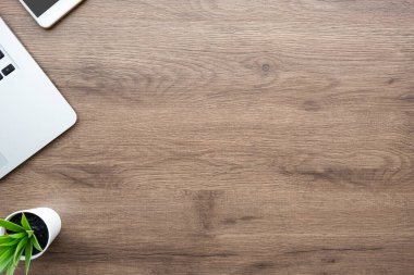 Laptop bilgisayar ve malzemelerle dolu ahşap ofis masası. Kopyalama alanı olan üst görünüm, düz yatay.