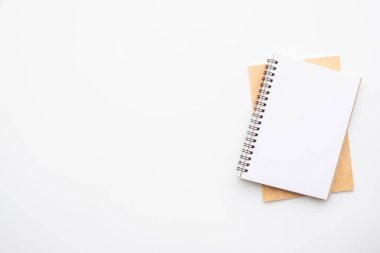 Boş defter beyaz ofis masasının üstünde. Kopyalama alanı olan üst görünüm, düz yatay.