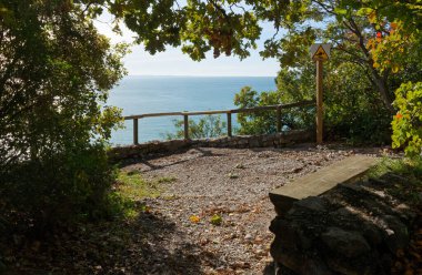 İtalya, Trieste yakınlarındaki Rilke panoramik doğa yolu boyunca tahta koltukla gölgeli bir bakış açısı.