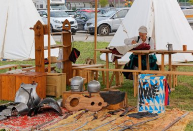 CORMONS, İtalya - 17 Ağustos 2019: Tarihi yeniden canlandırma sırasında bir kampta dikiş diken kız