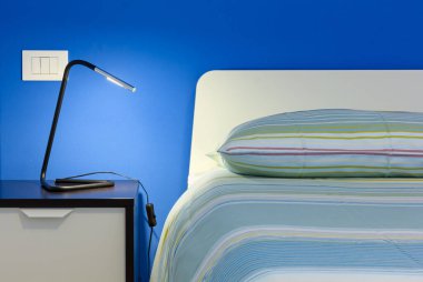 Modern bir yatak odasında çift kişilik yatak başlığı ve komodinin ayrıntıları.