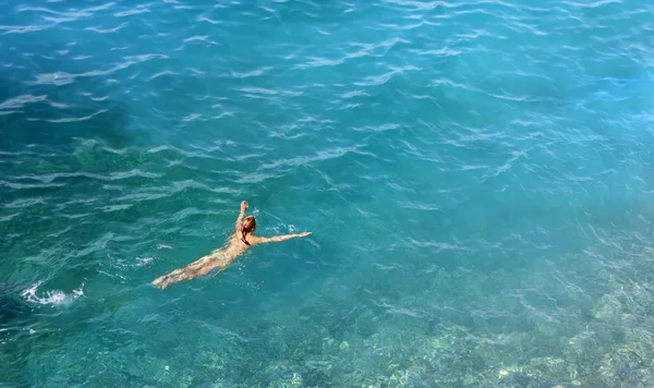 Giovane donna che nuota in acqua turchese — Foto Stock