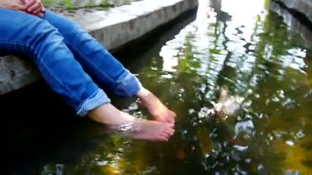 Eine Person taucht die Beine ins Wasser — Stockvideo