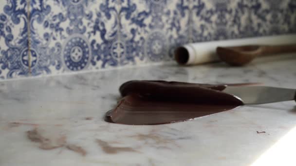 自家製の料理職人が背景の青と白のタイルと大理石のカウンターに滑らかな暗いチョコレート菓子を焼戻し. — ストック動画