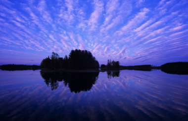 Bulutlar ve ay göl suyuna yansıyor.