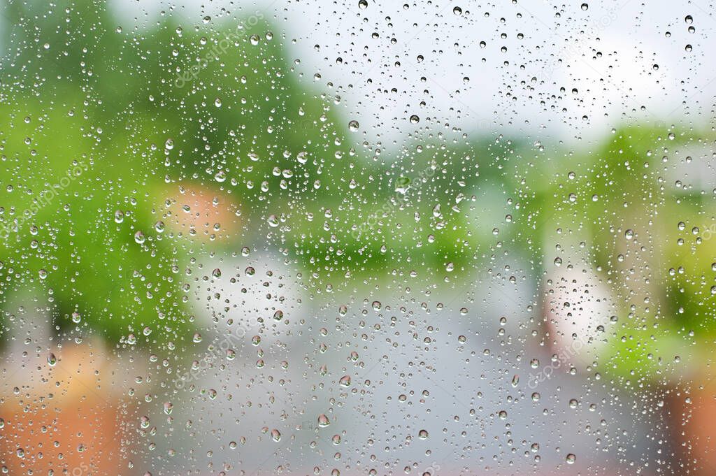 Raindrops on window with green defocused background.