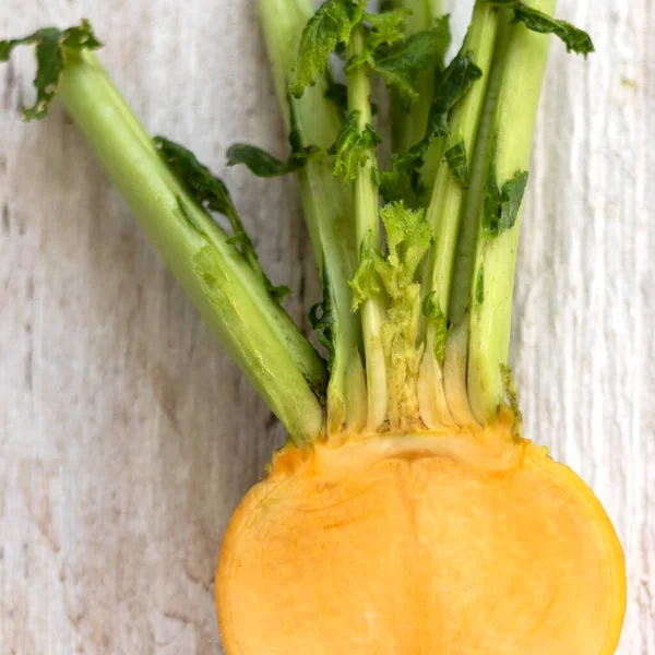 Rebanada de nabo amarillo con hojas sobre un fondo de madera blanca. Vitaminas útiles de hortalizas de raíz durante todo el año — Foto de Stock