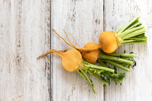 Slice of yellow turnip with leaves on a white wooden background. Useful vitamins from root vegetables all year round — Stock Photo, Image