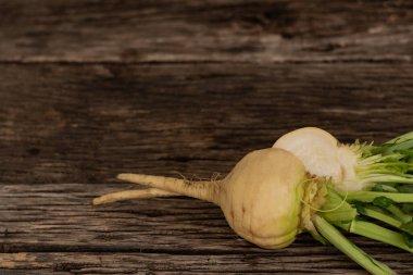 Kesik beyaz şalgam eski ahşap tahtaların üzerinde duruyor. Bahçede yetişen faydalı bir sebze kökü.