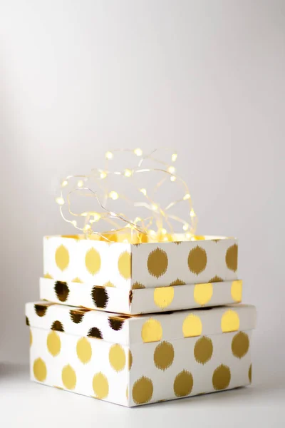 Hermosa caja de regalo con un patrón dorado sobre un fondo blanco y con guirnaldas Fotos De Stock