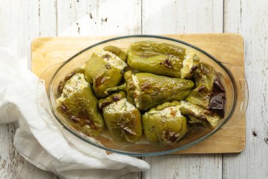 Biber, beyaz peynir, otlar, sarımsak. Mevsimlik yerel sebzelerle hazırlanmış cam tabak. Beyaz tahta arkaplan.