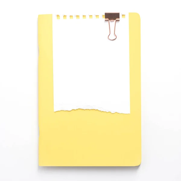 Um bloco de notas amarelo e dois clipes de papel de cobre estão em um fundo branco, vista superior. Papelaria e minimalismo — Fotografia de Stock