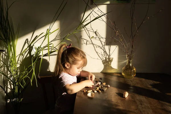 La chica juega con masa rosa salada en la mesa de la cocina. Las manos moldean la arcilla con sus propias manos para crear juguetes caseros de cintura cero. Lección creativa con una prueba de productos naturales. Desarrollo de Imagen De Stock