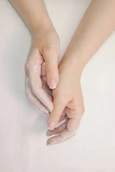 Mãos femininas em creme branco, sobre um fundo branco. — Fotografia de Stock