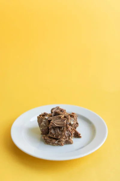 Ragoût de bœuf en conserve sur assiette blanche avec feuille de persil, fond jaune — Photo