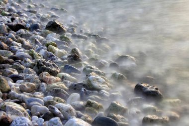 Deniz kıyısı. Kayaları yalayan deniz dalgaları. 