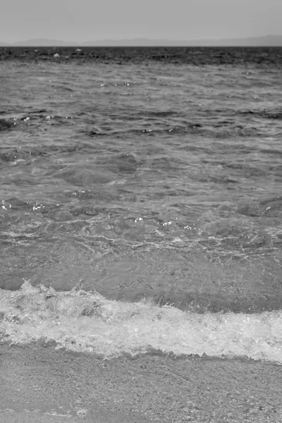 Vague de la mer sur la plage de sable noir et blanc — Photo