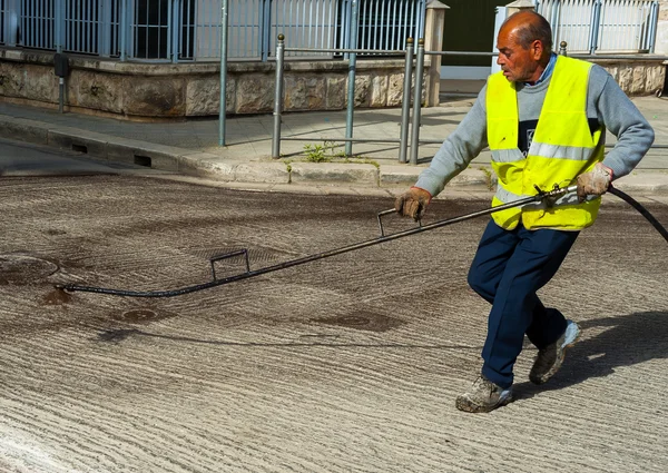 Emulsión del betún de pulverización del trabajador del camino con la lanza de pulverización manual antes de aplicar una nueva capa de asfalto — Foto de Stock