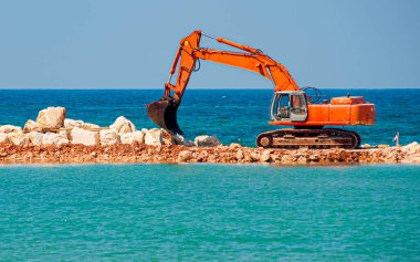 Rıhtımı ağır kazıcı makinesiyle inşa etmek. Kazıcının egzoz borusundan çıkan hava türbülansına dikkat edin.