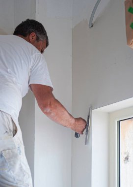 Sıvacı malayla duvarları düzleştiriyor.