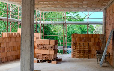 Bir inşaat alanında tuğla, kürek, süpürge ve diğer iş aletleri yığını.