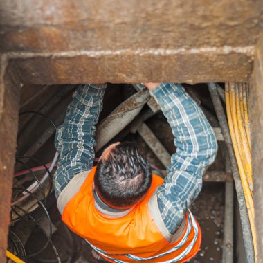 İşçi, yeni fiber optik hattı etkinleştirmek için telefon hattının rögar kapağında çalışıyor.