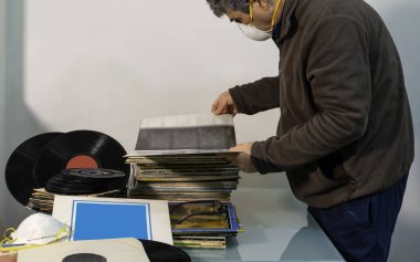 Modugno, İtalya - 12 Mart 2020: Coronavirus pandemik karantina COVID-19 için evde. Tutkulu bir ses delisi, plak koleksiyonunu sipariş ediyor.