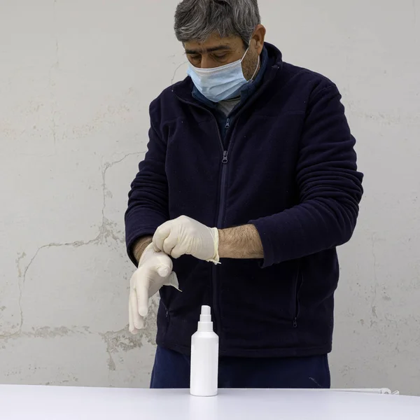 person puts on white latex gloves to contain the spread of the coronavirus infection