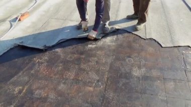 İşçiler hasarlı katmanı bir binanın düz çatısından çıkarıyorlar.