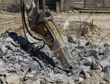 İnşaat alanındaki beton döküntüler, ezilmiş beton levhalar ve çelik çubuklar, hidrolik çekiçli yıkım kazıcısı geri dönüşümlü çelik çubukla güçlendirilmiş betonu tahrip ediyor..