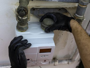 İşçi mührü boru ve gaz sayacının arasına yerleştiriyor. Seçici odak