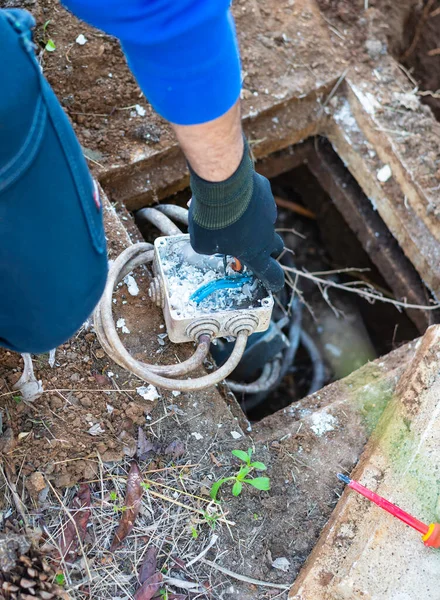 電気技師は 電気ケーブルを水から保護するために絶縁ゲルで密封された電気接合ボックス内のケーブルの電気接続を修理します 選択手フォーカス — ストック写真