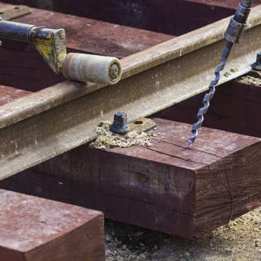 Rayları sürgüleyen demiryolu işçileri. Hafif portatif sondaj makinesi olan detaycı.