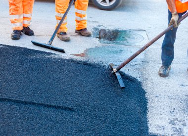 Yol işçilerinin çalışma grubu yolun bir kısmını taze asfalt ile yeniliyor ve tamir için düzleştiriyor..