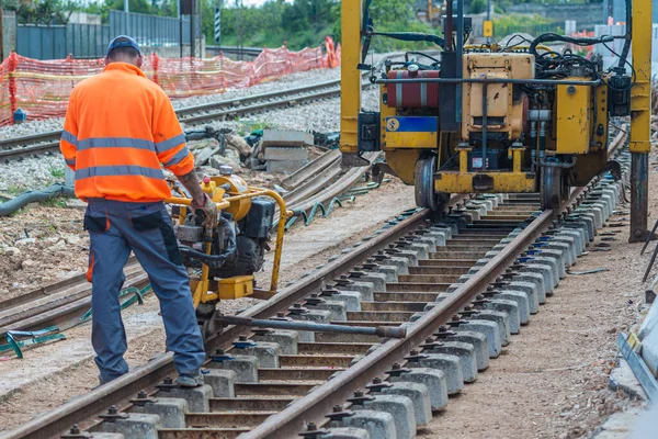 Rayları sürgüleyen demiryolu işçileri. Mekanik cıvata anahtarı olan detaycı işçi