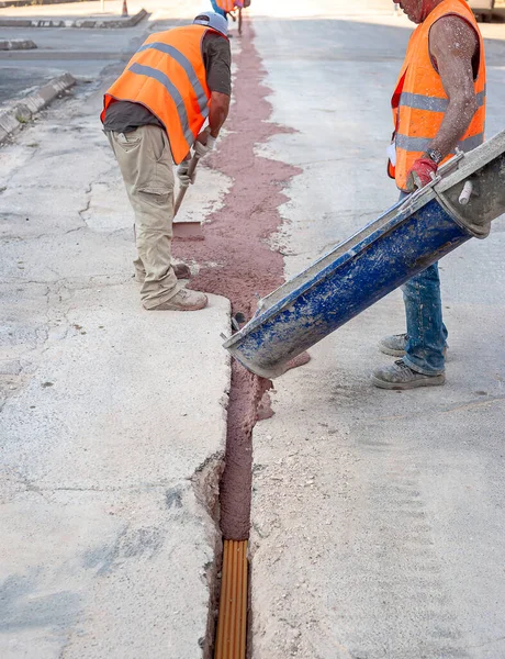 光纤电缆埋在混凝土的微沟槽中红色的一名工人 — 图库照片