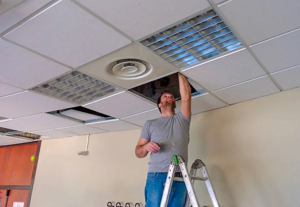 Builder putting or repairing up a suspended ceiling