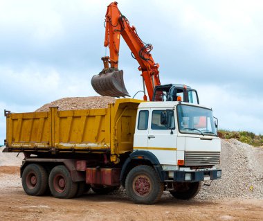Ekskavatör inşaat alanında bir kamyona yükleniyor