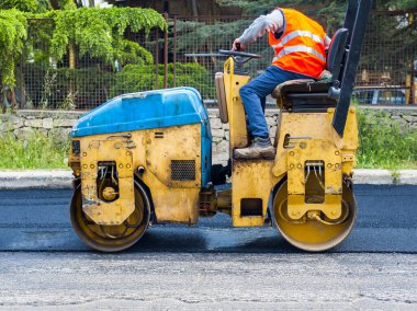 Asfalt kaldırımda hafif titreşimli paten sıkıştırıcı işçisi yol onarımı için çalışır